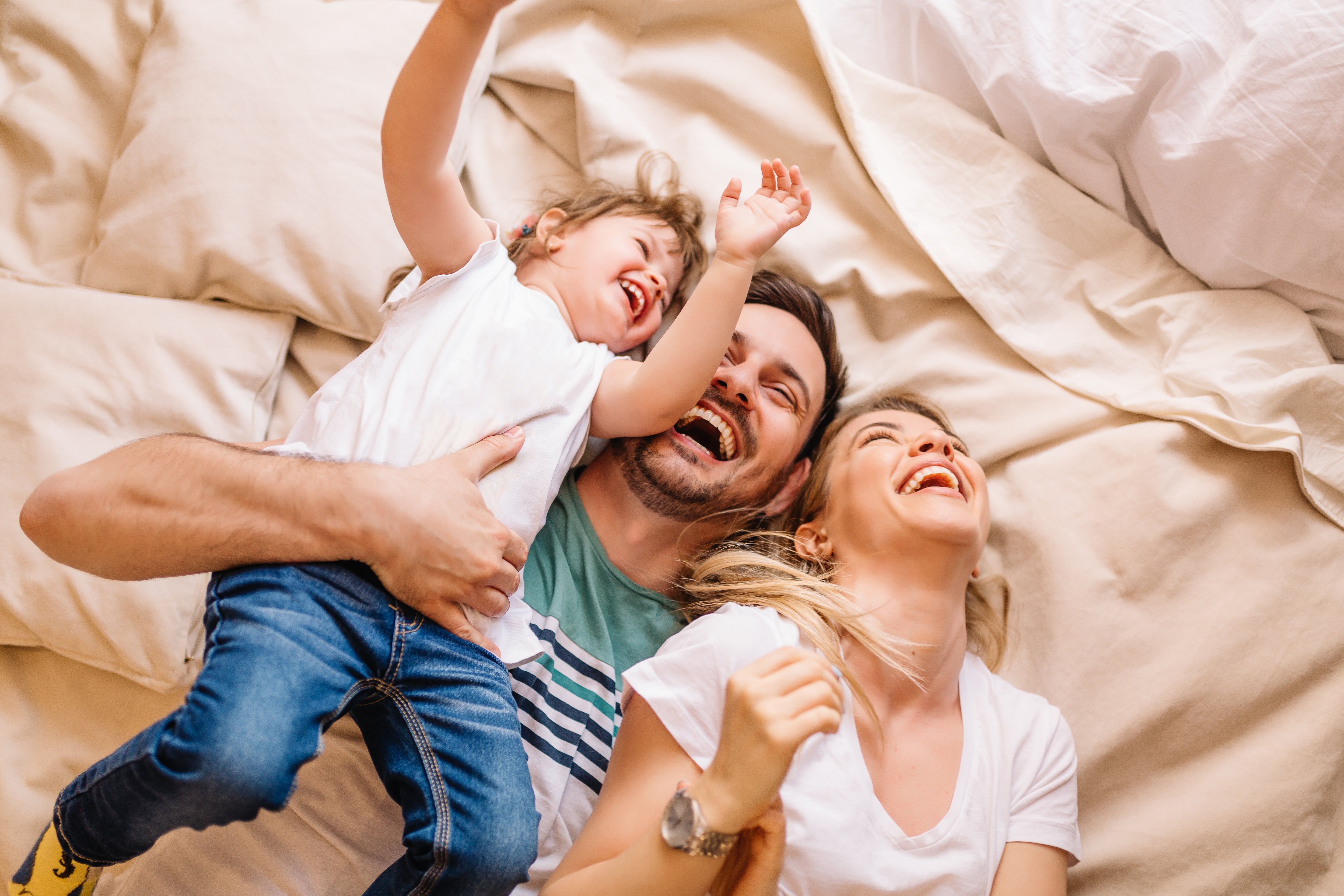 Drei Personen liegen gemeinsam auf einem Bett. Das Motiv steht für Familienplanung und das Leben mit einer von-Willebrand-Erkrankung.